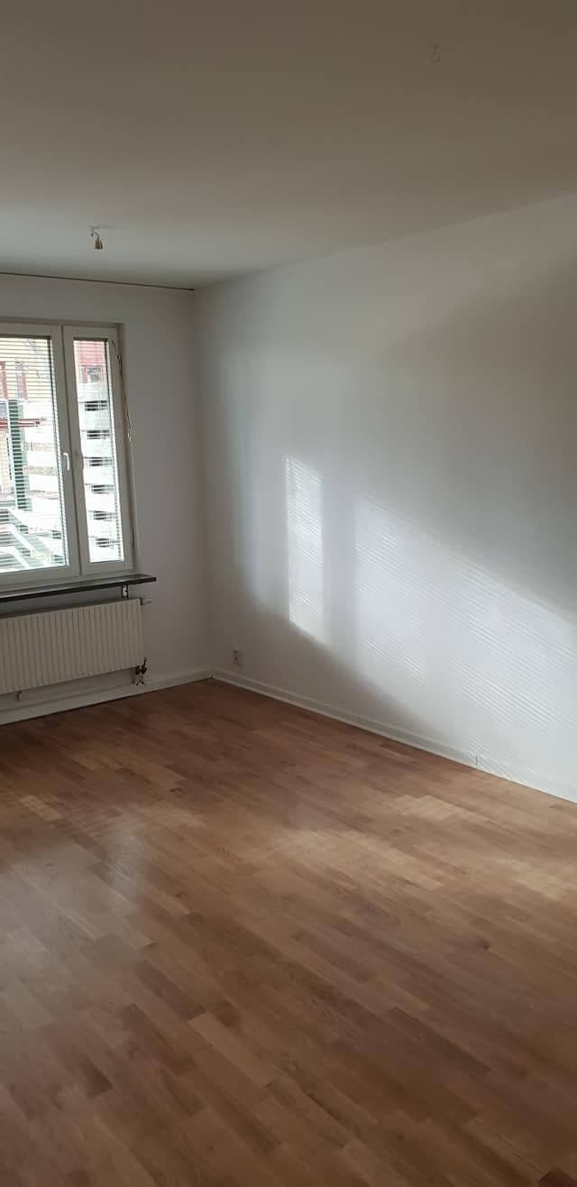 Nymålat rum med fönster och parkettgolv