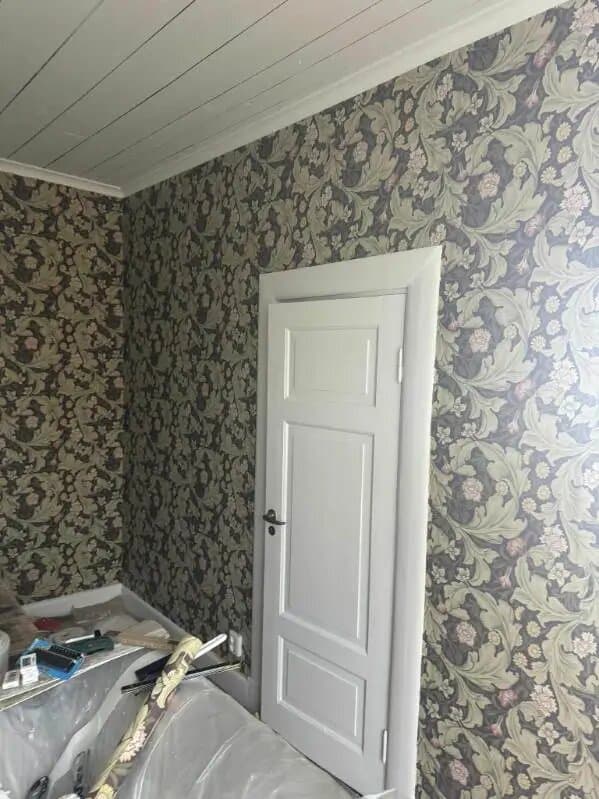 Nysatt tapet med mörkt blommönster runt en vit spegeldörr
